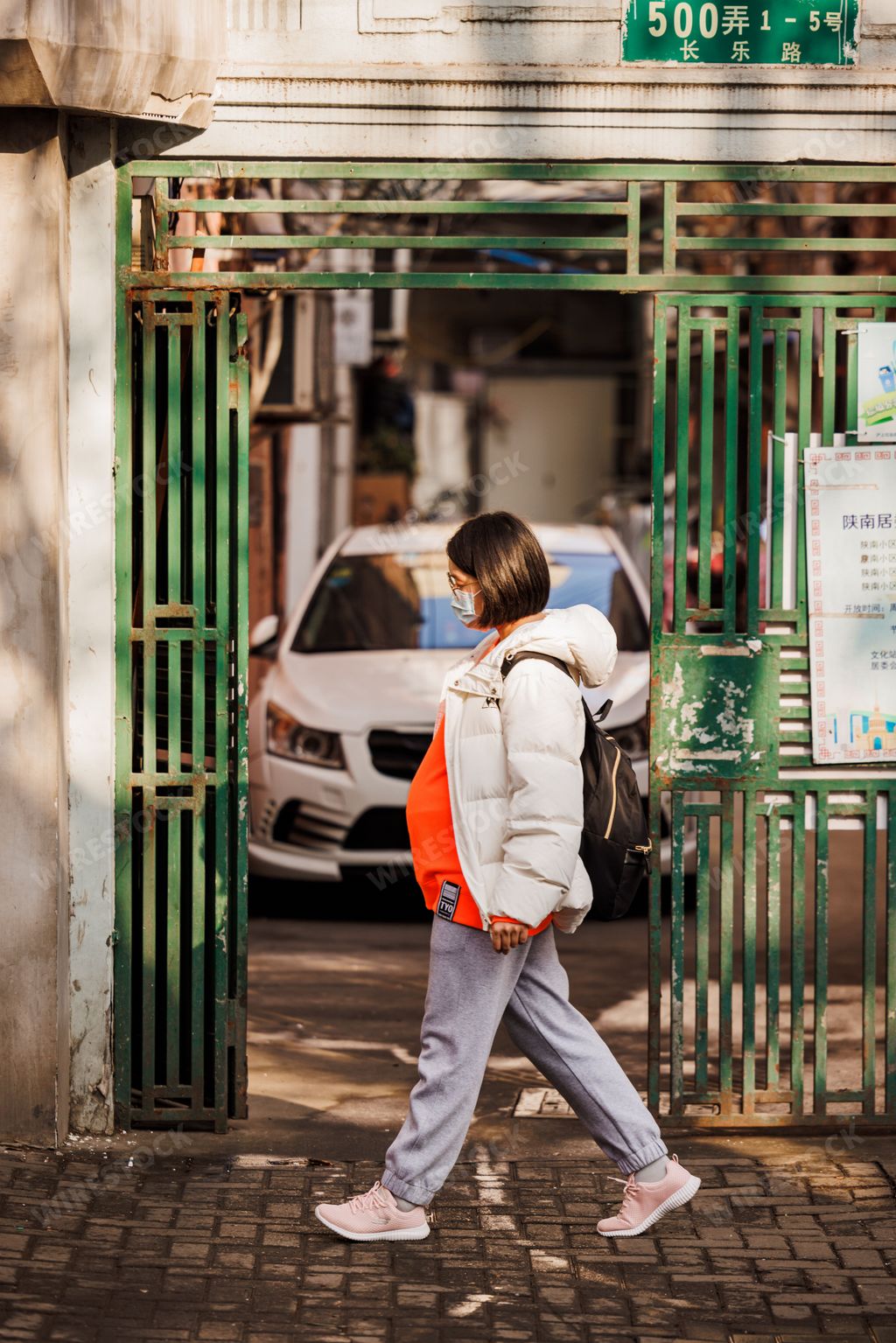A vertical shot of a young pregnant woman walking on the street in Shanghai, China