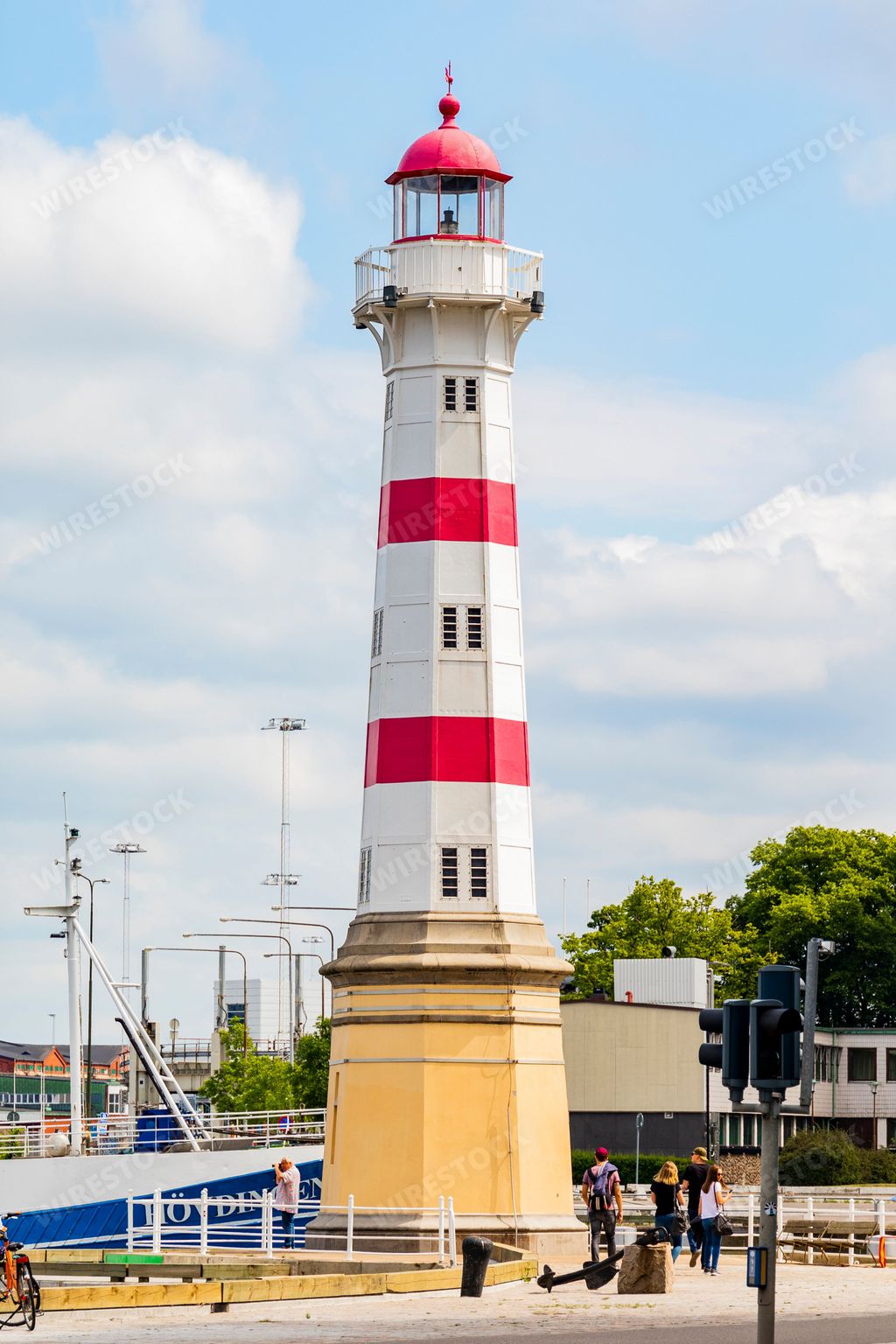 A vertical shot of a red and white lighthouse in the harbour of Malmo, Sweden