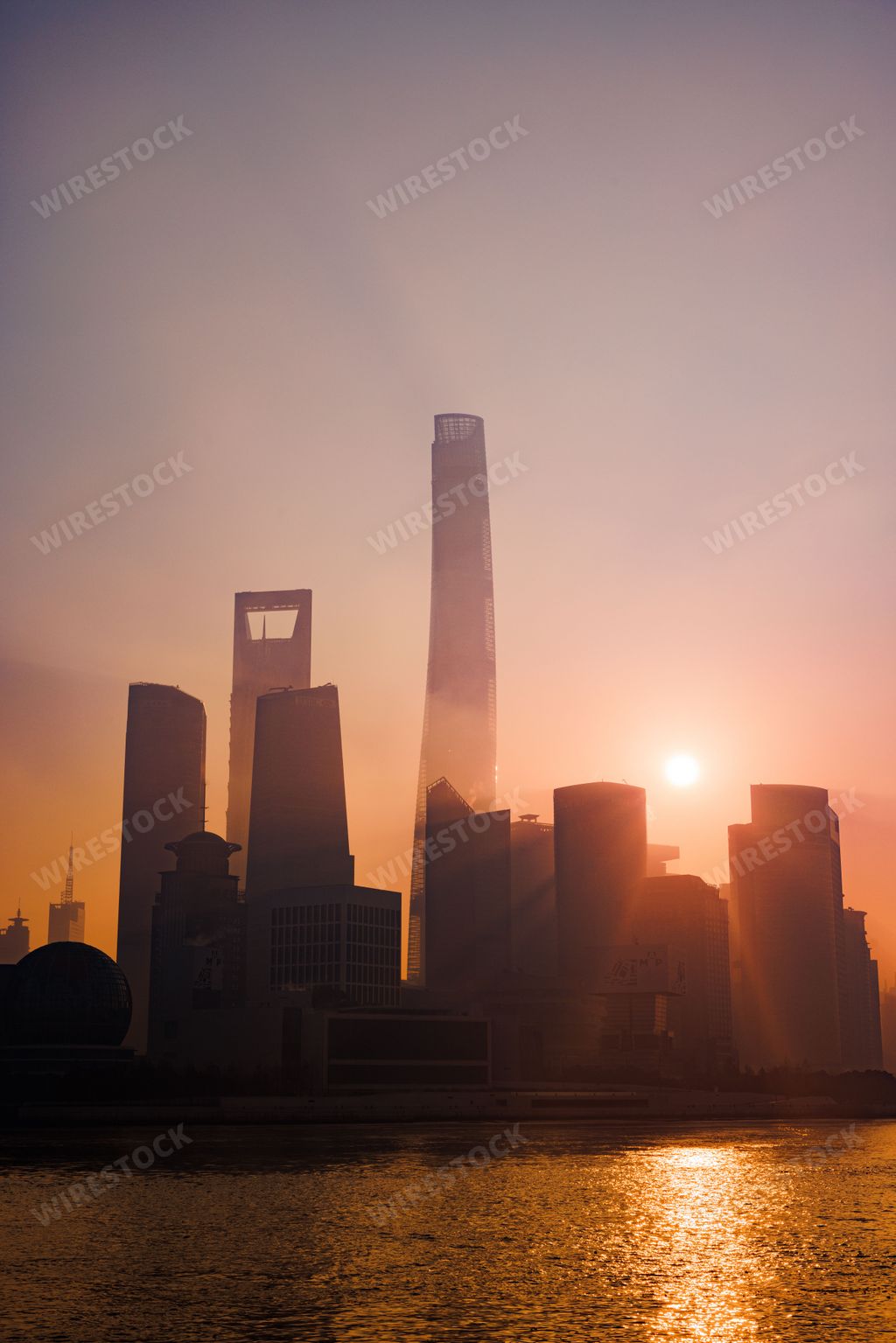 A vertical shot of Pudong Skyline skyscrapers by the river during sunrise in Shanghai