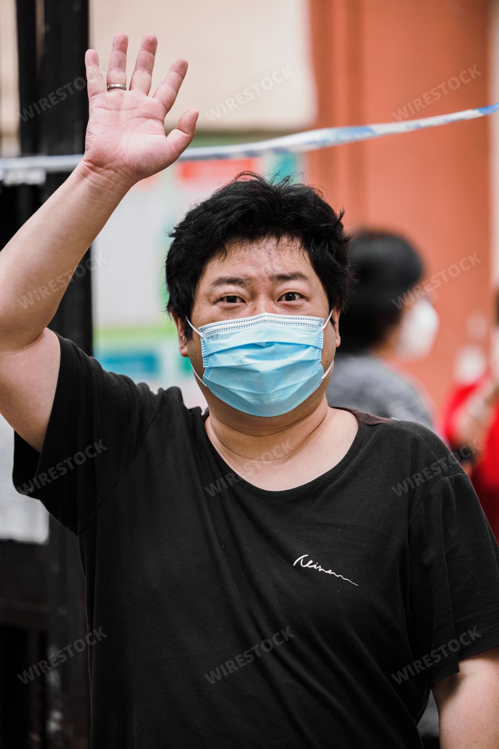 A vertical shot of a Chinese man with face mask walking the streets of Shanghai while waving his arm during COVID 19 pandemic