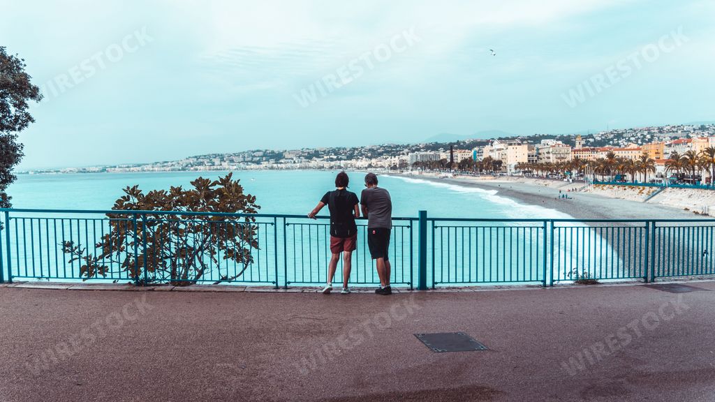Two people overlooking the sea standing at a railing in Nice, France