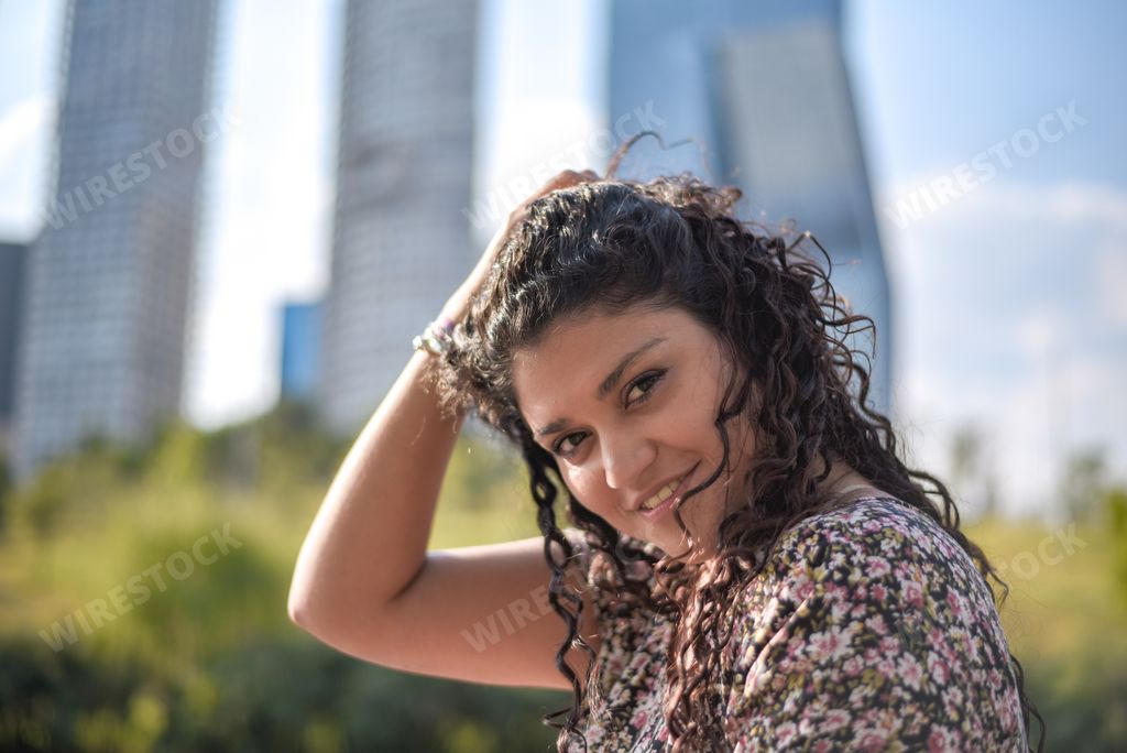 A portrait of a smiling Hispanic female with curly hair