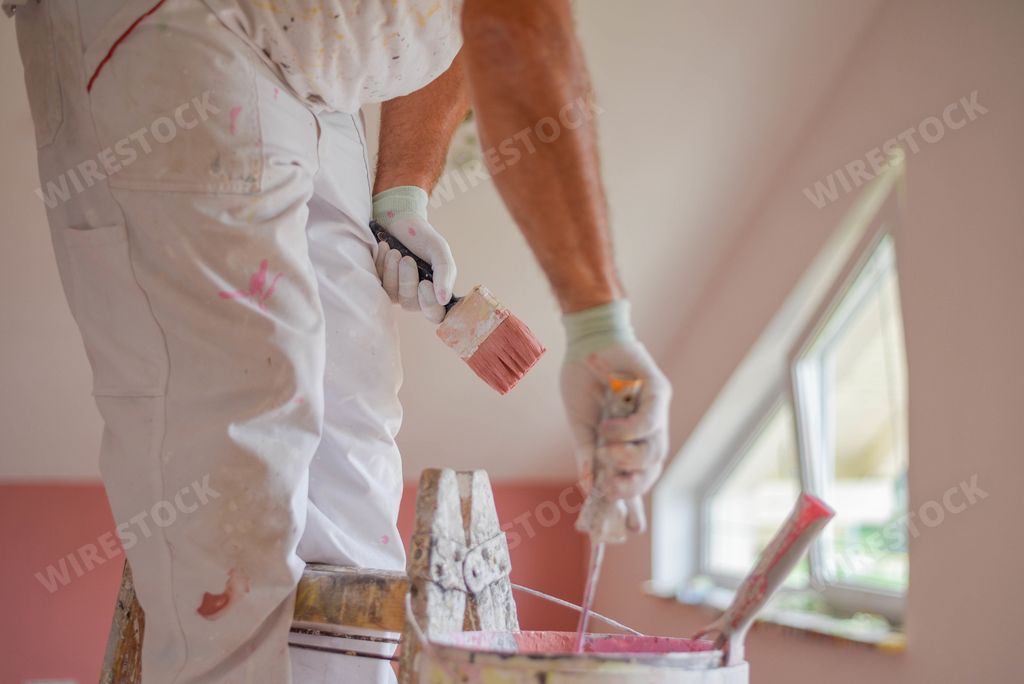 A closeup shot of a handyman holding a pink paintbrush