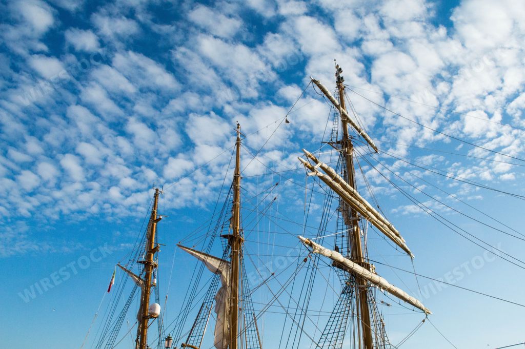 A low angle shot of a large old ship sails on a cloudy sky background