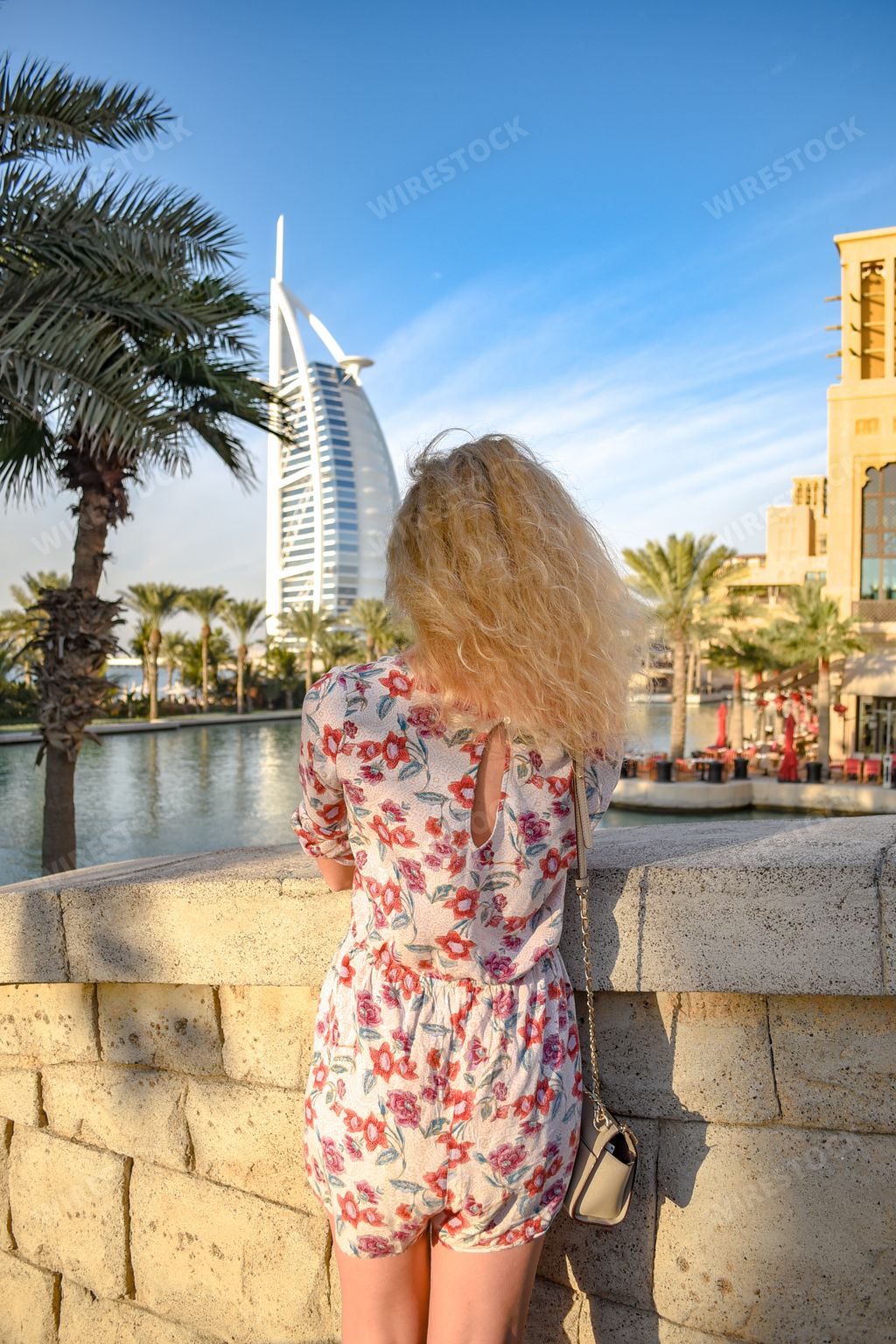 A back view of a young blonde female enjoying the view of Burj al Arab in Dubai