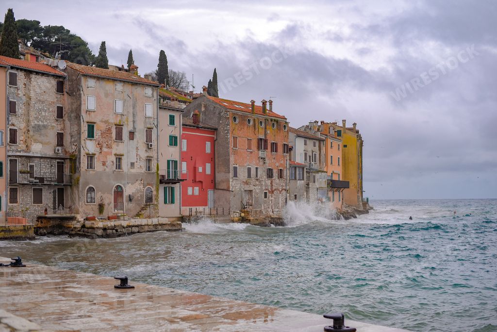 A beautiful view of Rovinj, Croatia with a wavy sea next to colorful buildings