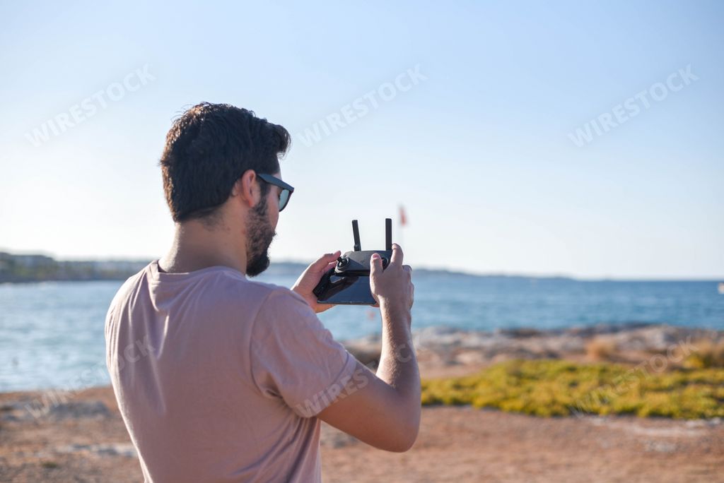 A young attractive sexy Hispanic man playing a game with a gamepad outdoors