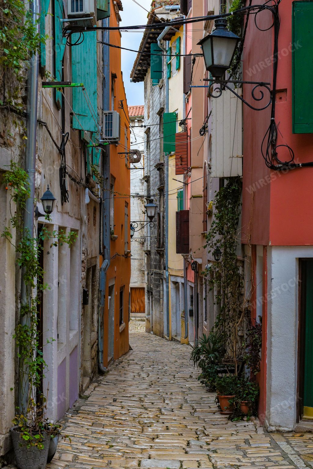 A beautiful vertical shot of a brick walkway in a narrow alley surrounded by colorful buildings in Rovinj, Croatia