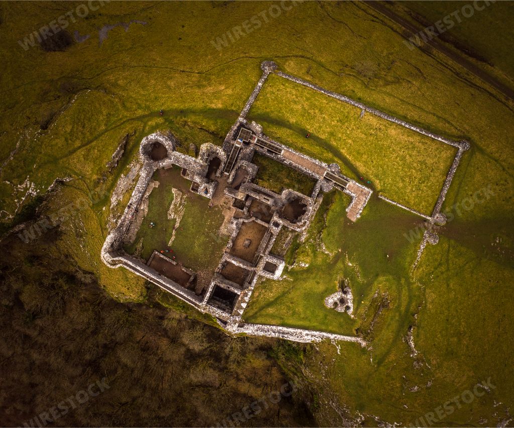 An overhead shot of the ruins of an old and abandoned castle in the middle of a grass-covered field