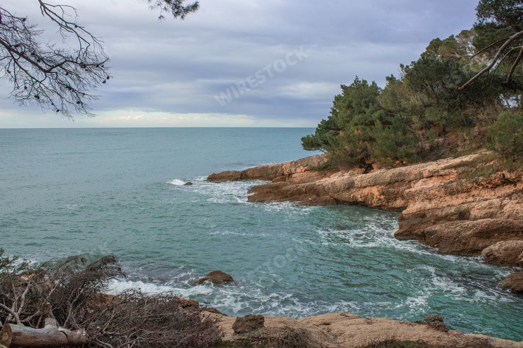 A beautiful shot of sea waves crashing on the rocks under a blue cloudy sky during the daytime