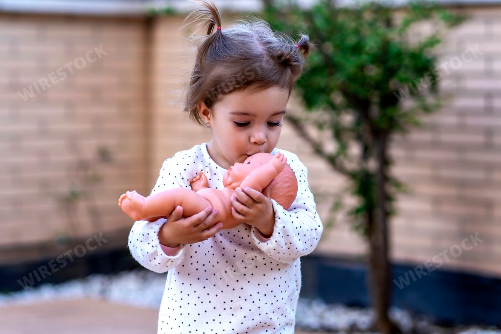 child girl kissing her doll