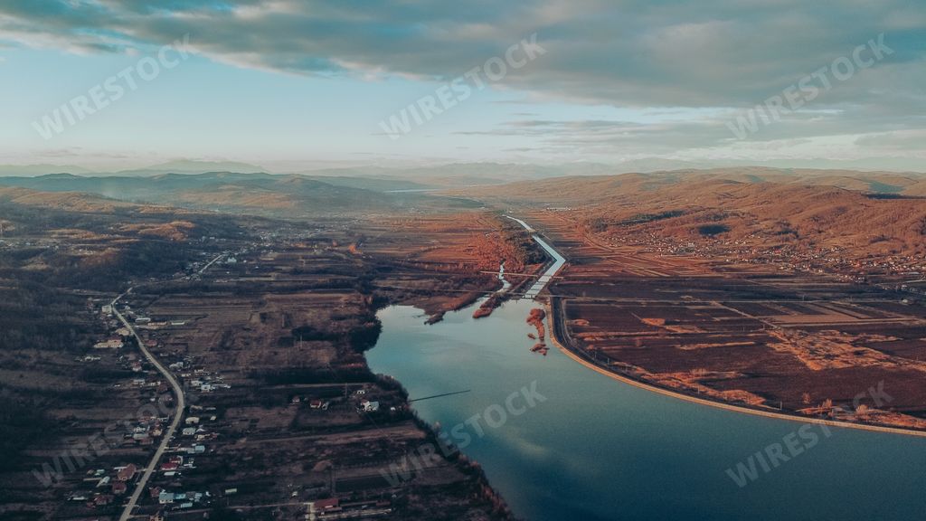 A beautiful aerial view of calm lake water and a small waterfront village under a cloudy sky