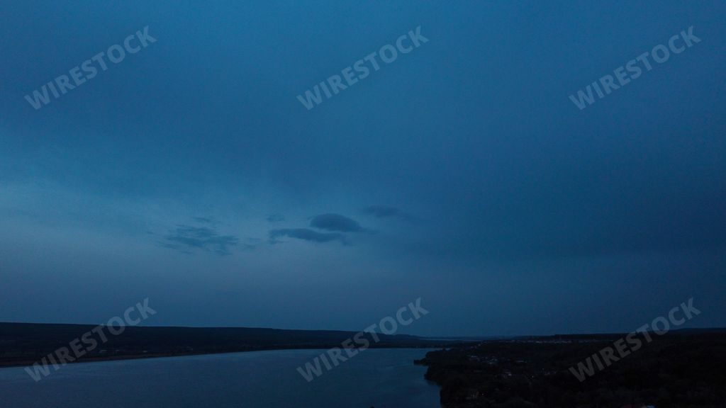 A beautiful scenery of a calm river and a vast landscape against a stormy sky background