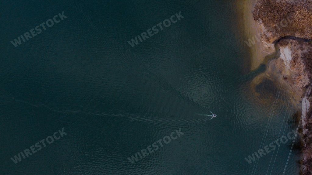 A beautiful aerial view of the boat driving on the ocean closer to the cliff on the shore