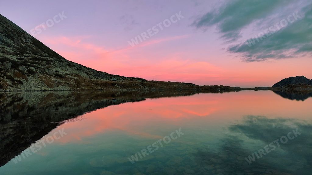 The lake with reflection in it with the rocks and sunset blue sky in the background